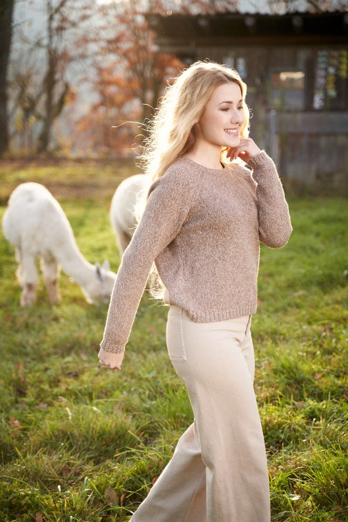 Vollansicht einer Frau die einen Wollpullover in der Farbe Beige trägt