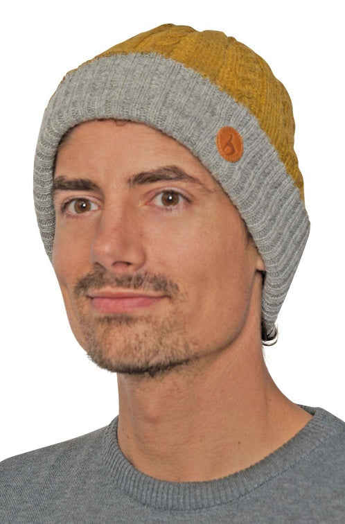 Portraitansicht eines Mannes der die wendbare Strickmütze SUAVE aus Alpaka in den Farben Gelb Silber trägt