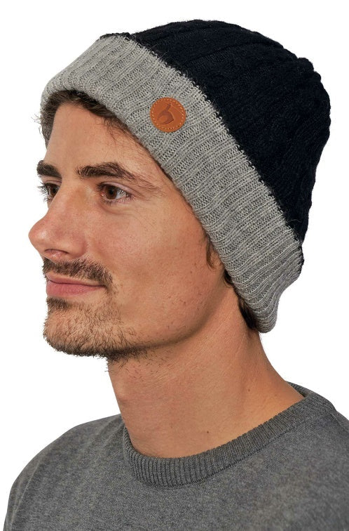 Portraitansicht eines Mannes der die wendbare Strickmütze SUAVE aus Alpaka in den Farben Schwarz Silber trägt