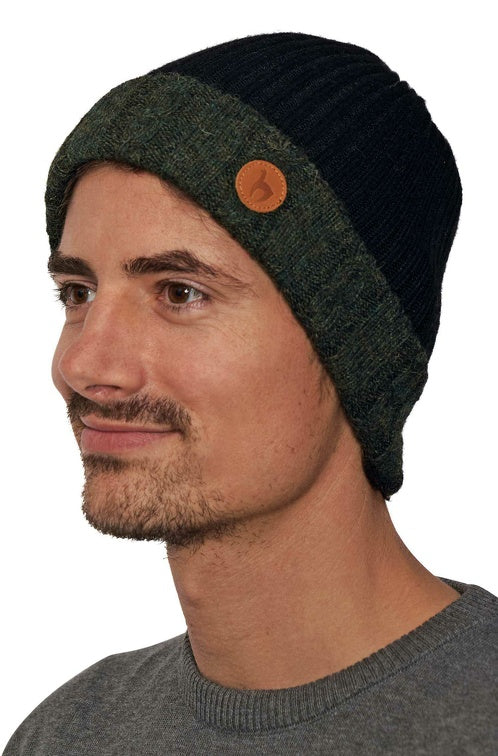 Portraitansicht eines Mannes der die wendbare Strickmütze SUAVE aus Alpaka in den Farben Tannengrün Schwarz trägt